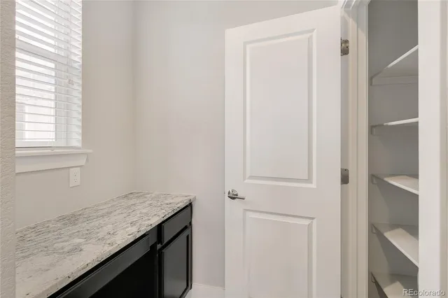 an empty room with wooden floor cabinet and windows