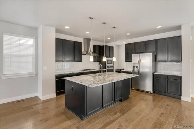 a large kitchen with kitchen island a large counter top stainless steel appliances and cabinets