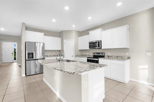 a kitchen with a sink a microwave a refrigerator and white cabinets