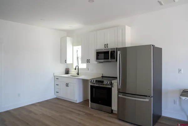 a kitchen with cabinets stainless steel appliances and wooden floor