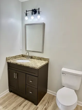 a bathroom with a granite countertop toilet sink and mirror