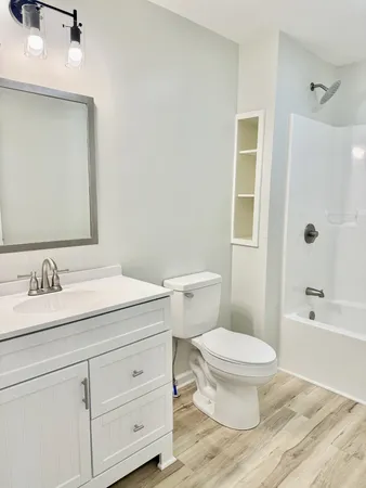 a bathroom with a granite countertop sink toilet a large mirror a bathtub and shower