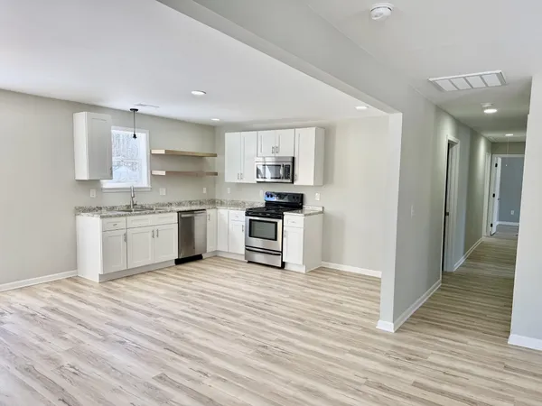 a kitchen with stainless steel appliances granite countertop a stove top oven a sink and white cabinets