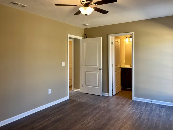 an empty room with wooden floor fan and windows