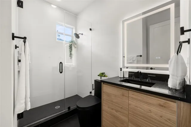 a bathroom with a granite countertop sink a toilet a mirror and shower