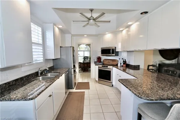 a kitchen with granite countertop a sink a counter top space appliances and cabinets
