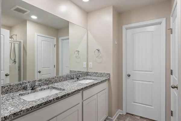 a bathroom with a granite countertop double vanity sink and a mirror
