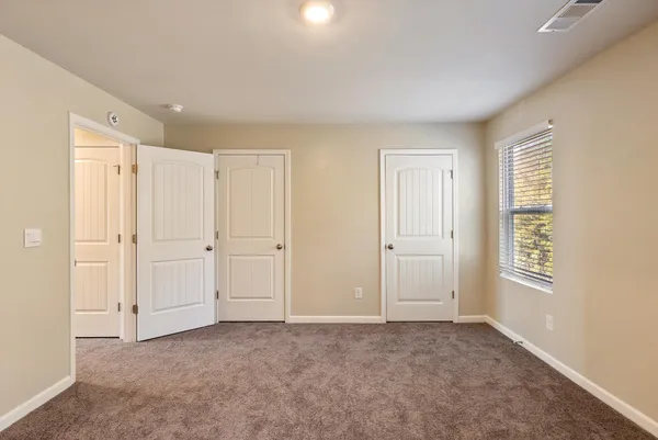 a view of an empty room with closet and a window