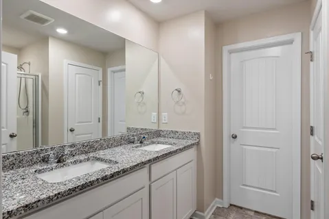 a bathroom with a granite countertop double vanity sink and a mirror