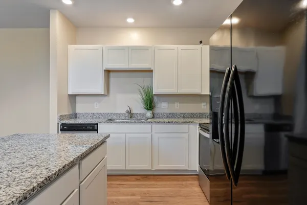 a kitchen with kitchen island granite countertop a sink a counter space stainless steel appliances and cabinets