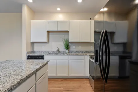 a kitchen with kitchen island granite countertop a sink a counter space stainless steel appliances and cabinets