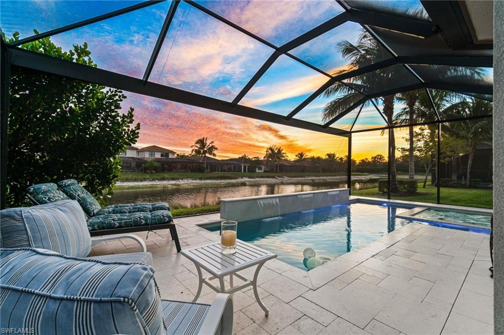 4318 Aurora Street Naples, FL 34119 - Photo 1 of 50 Stunning sunset and lake views from the screened lanai featuring a custom pool and spa, elegant stone pavers and a peaceful outdoor seating area, perfect for enjoying Florida evenings.