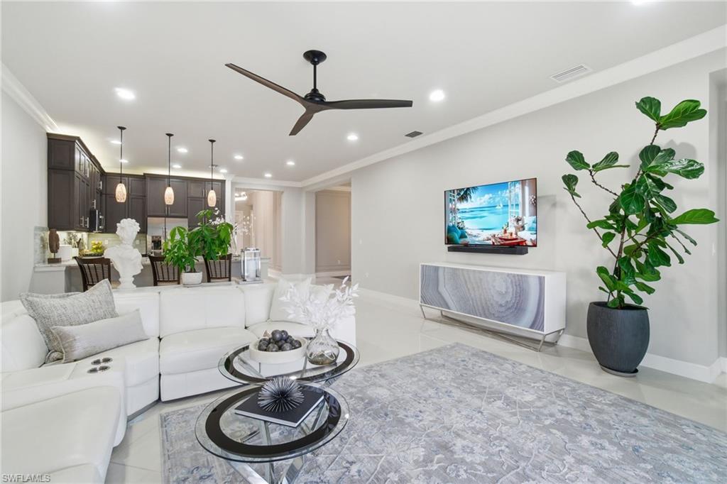 4318 Aurora Street Naples, FL 34119 - Photo 14 of 50 Elegant open-concept living space with crown molding, recessed lighting, modern ceiling fan, and light tile flooring, ideal for relaxed living and entertaining.