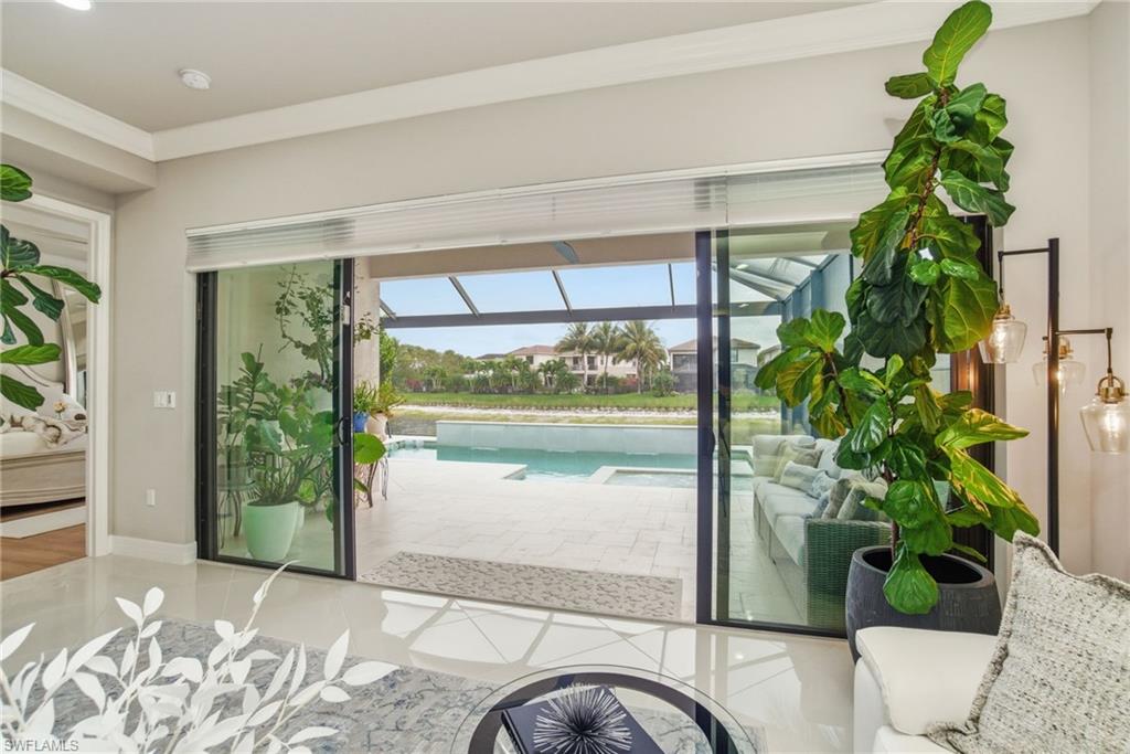 4318 Aurora Street Naples, FL 34119 - Photo 16 of 50 Bright living space with crown molding, tile floors, and seamless access to the lanai, pool, and lake views