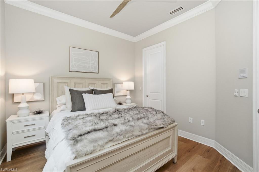4318 Aurora Street Naples, FL 34119 - Photo 33 of 50 Thoughtfully designed bedroom with crown molding, wood-look floors, and soft neutral tones.
