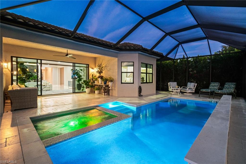 4318 Aurora Street Naples, FL 34119 - Photo 35 of 50 Evening view of the screened pool and spa with ambient lighting and covered outdoor living