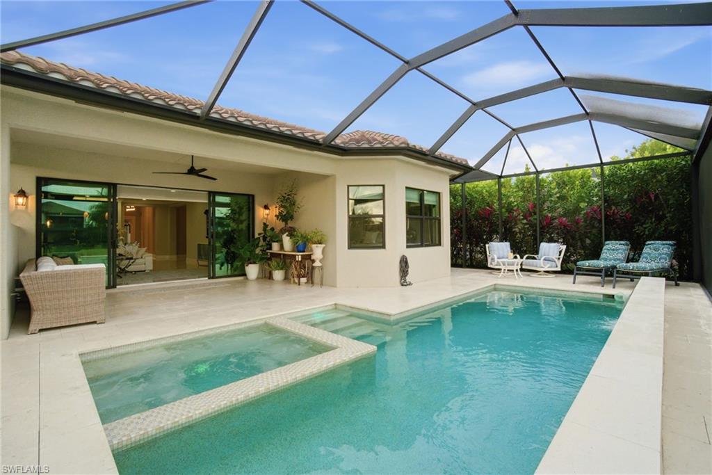 4318 Aurora Street Naples, FL 34119 - Photo 37 of 50 View of swimming pool featuring glass enclosure, a sunroom, a patio area, and a pool with connected hot tub