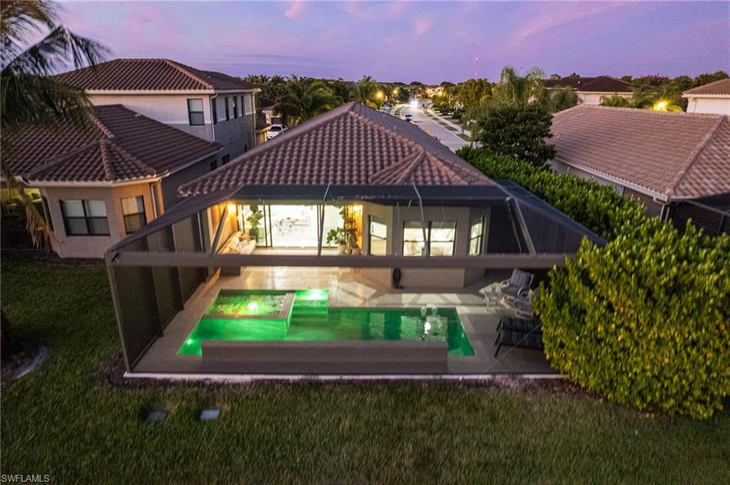 4318 Aurora Street Naples, FL 34119 - Photo 40 of 50 Twilight rear view highlighting the screened lanai, custom pool and spa, and serene outdoor living space.