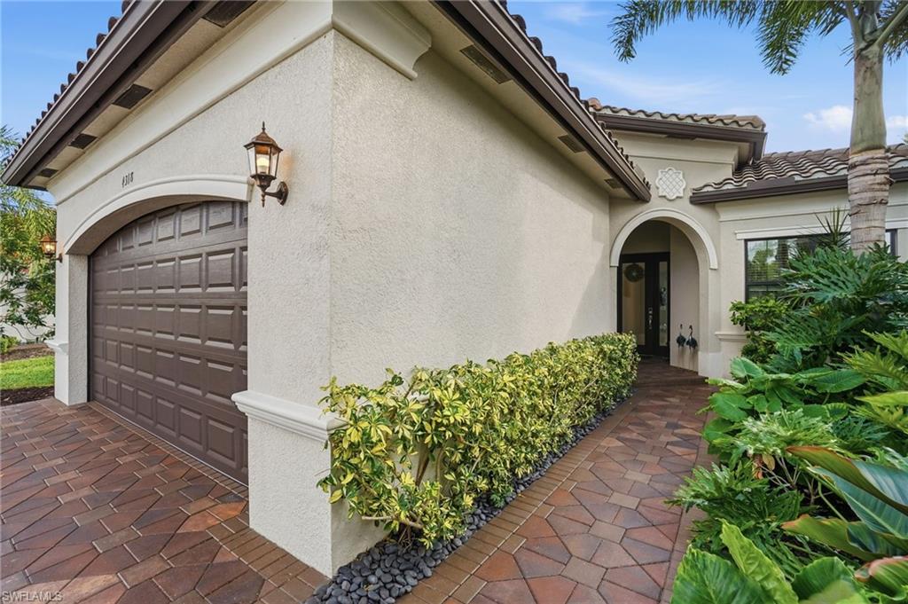 4318 Aurora Street Naples, FL 34119 - Photo 6 of 50 Elegant front entry featuring arched architecture, title roof, brick pavers, and manicured tropical landscaping.
