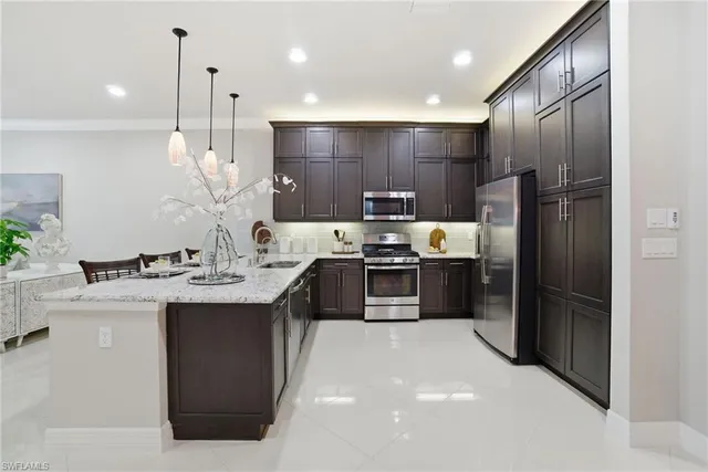 a kitchen with kitchen island stainless steel appliances a sink a counter top space cabinets and appliances