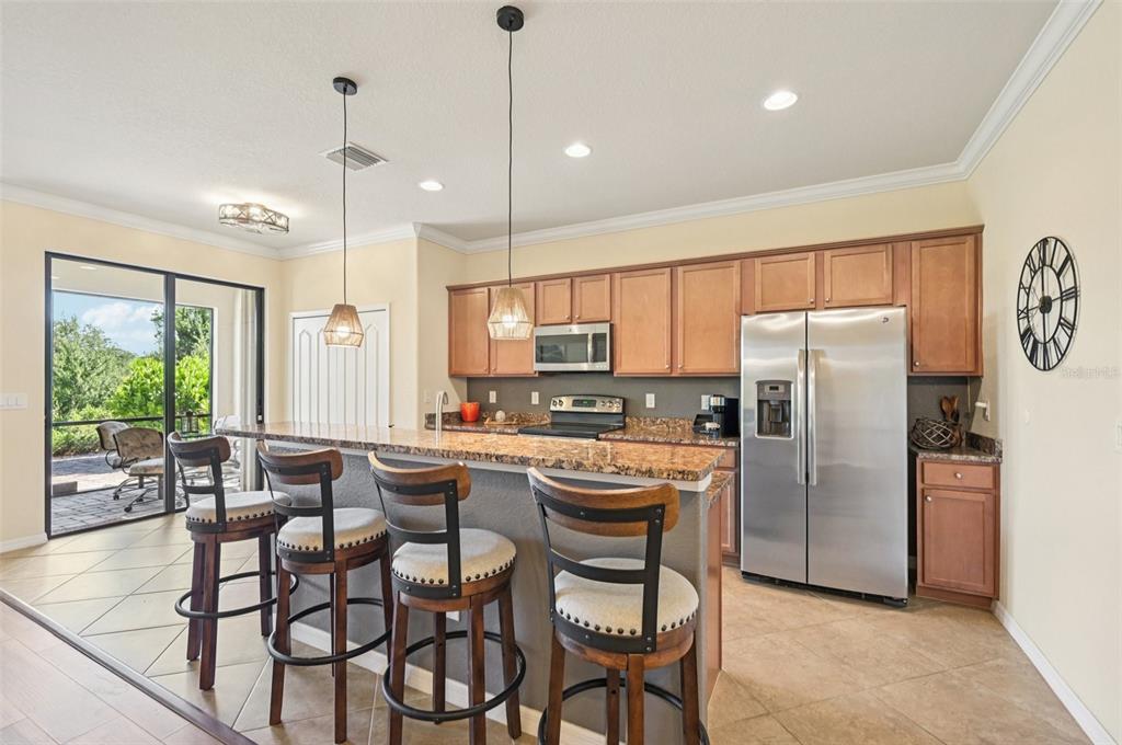 12680 Richezza Drive Venice, FL 34293 - Photo 13 of 57 a kitchen with stainless steel appliances granite countertop a refrigerator a oven a sink a dining table and chairs with wooden floor