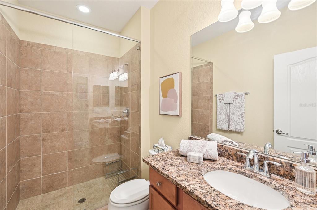 12680 Richezza Drive Venice, FL 34293 - Photo 23 of 57 a bathroom with a granite countertop sink a toilet a mirror and shower
