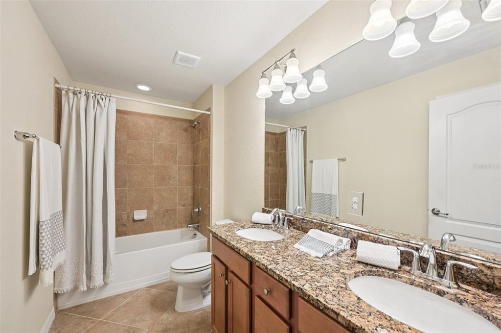 12680 Richezza Drive Venice, FL 34293 - Photo 24 of 57 a bathroom with a granite countertop double vanity sink toilet and shower