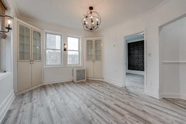 an empty room with wooden floor cabinet and windows