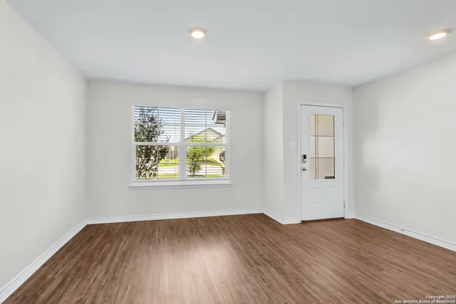 an empty room with wooden floor and window