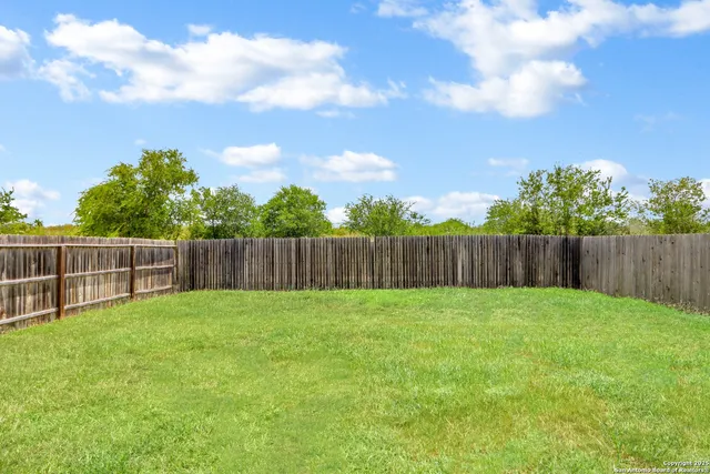 a view of a backyard with a house and wooden fence