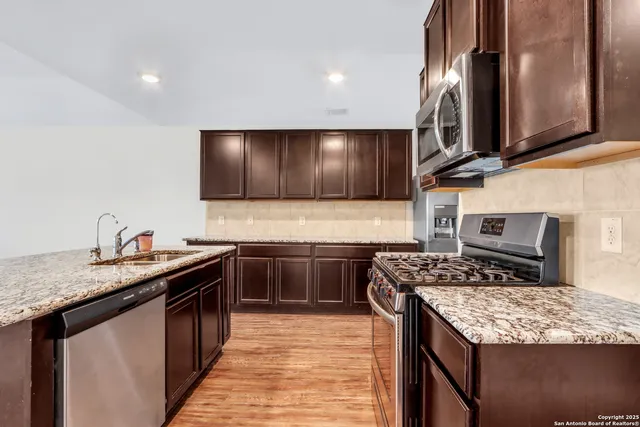 a kitchen with stainless steel appliances granite countertop a stove a sink and a microwave