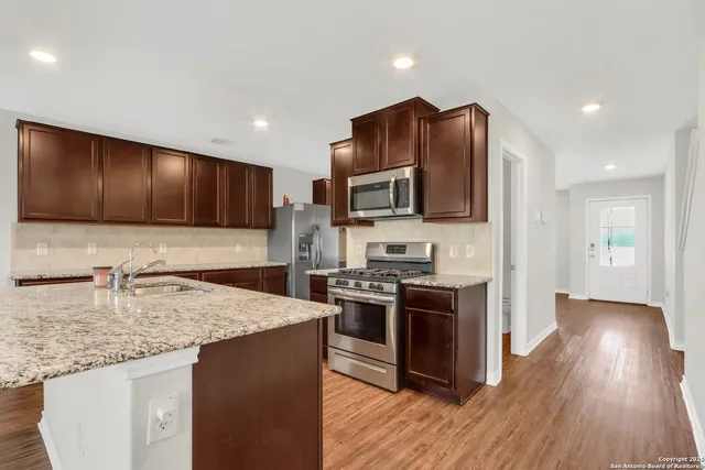 a kitchen with stainless steel appliances granite countertop wooden cabinets a stove top oven a sink and dishwasher