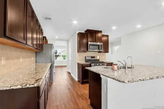 a kitchen with kitchen island granite countertop a sink stove and refrigerator
