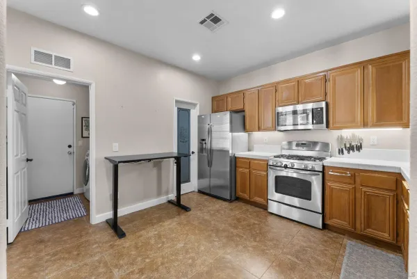 a kitchen with granite countertop a sink cabinets stainless steel appliances and a window