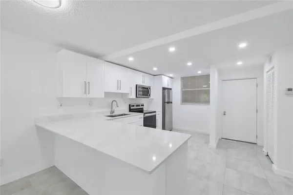 a kitchen with stainless steel appliances kitchen island sink refrigerator and cabinets