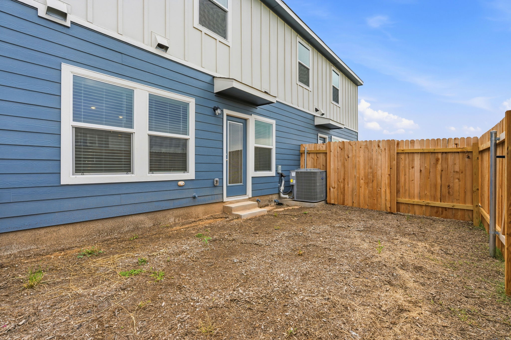164 Cinnabar Lane, Unit 4 Kyle, TX 78640 - Photo 23 of 23 Private fenced yard with a wood privacy fence, blue horizontal siding, white trim windows, and a glass-paneled door