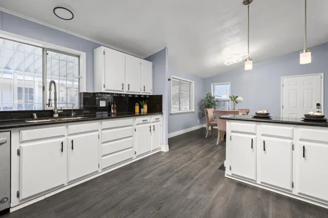 a kitchen with granite countertop white cabinets white appliances a sink and a window