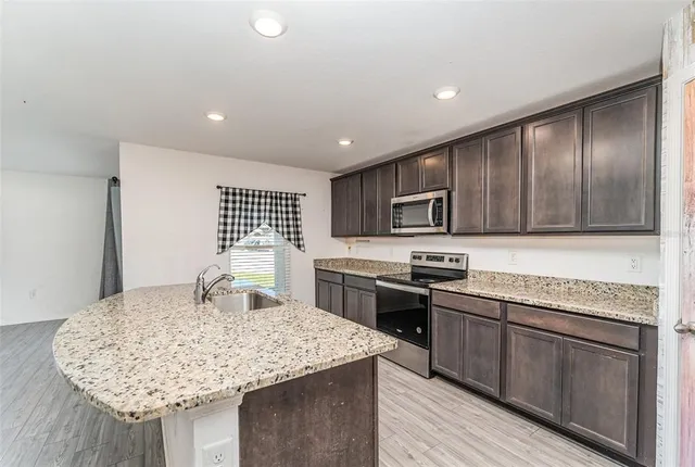 a kitchen with stainless steel appliances granite countertop a sink dishwasher stove and refrigerator with wooden floor