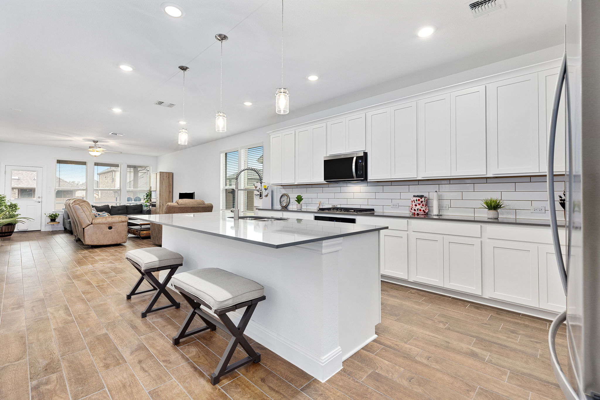 116 Raleigh Drive Georgetown, TX 78633 - Photo 3 of 28 An open-concept living area boasts a sleek kitchen island and warm plank flooring throughout.
