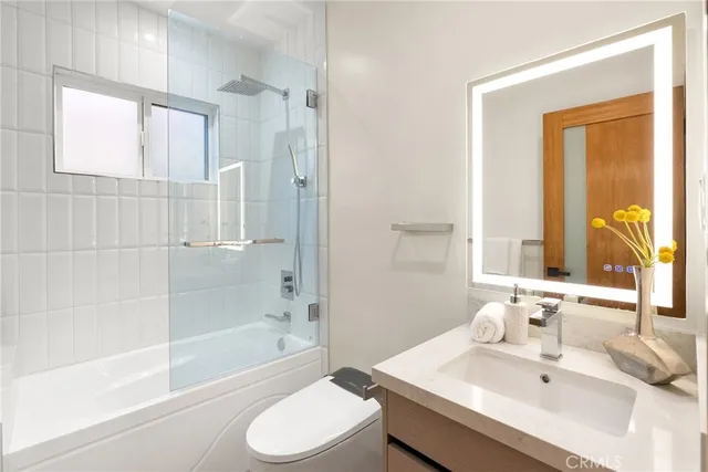 a bathroom with a bathtub shower sink vanity and toilet