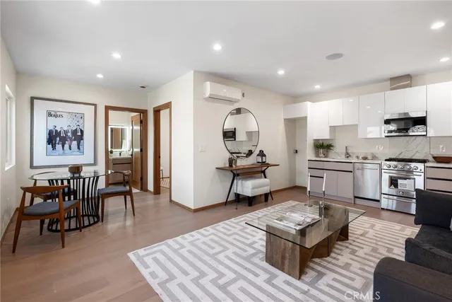 a living room with furniture and kitchen view with wooden floor