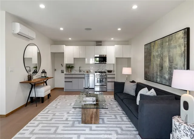 a living room with furniture a rug kitchen view and a large window