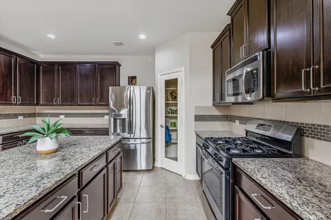 a kitchen with stainless steel appliances granite countertop a stove a refrigerator and a sink