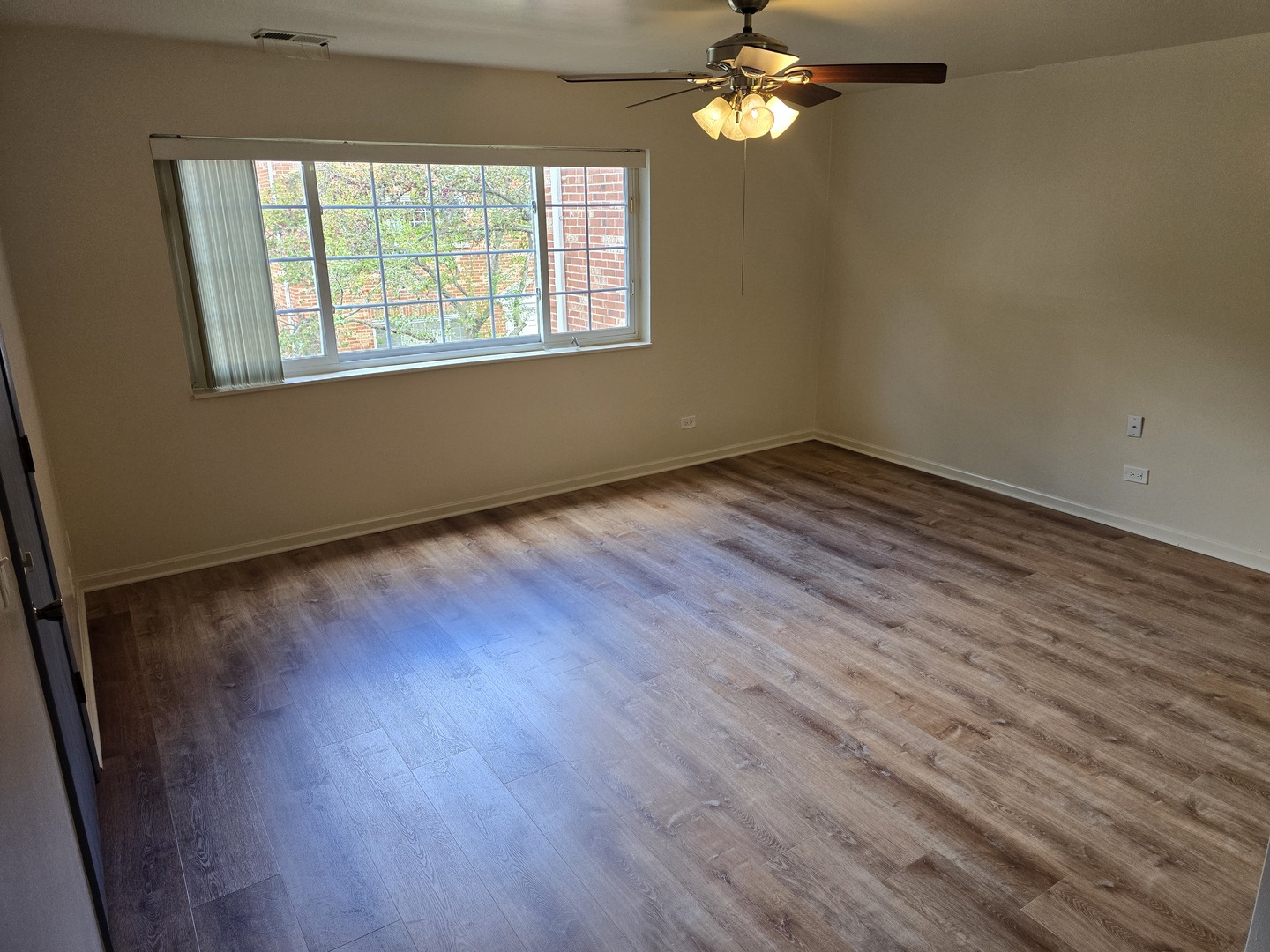 6882 West Touhy Avenue, Unit D Niles, IL 60714 - Photo 2 of 9 a view of an empty room with wooden floor and a window