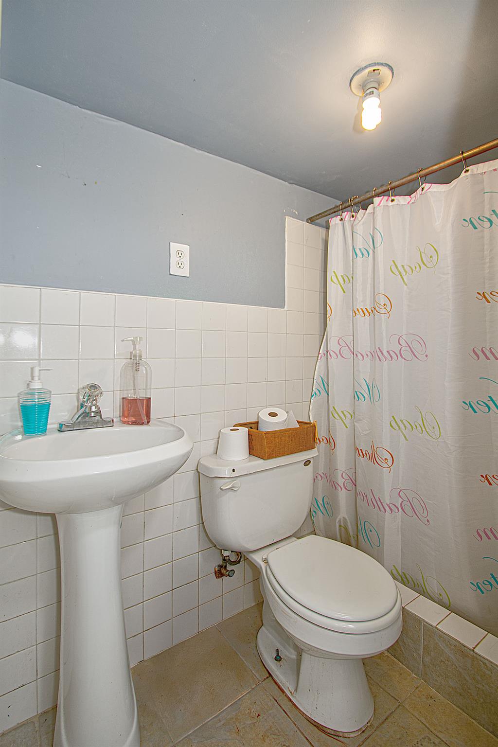 80-63 87th Road Queens, NY 11421 - Photo 19 of 24 a bathroom with a sink a toilet and shower curtain