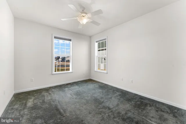 an empty room with windows and ceiling fan