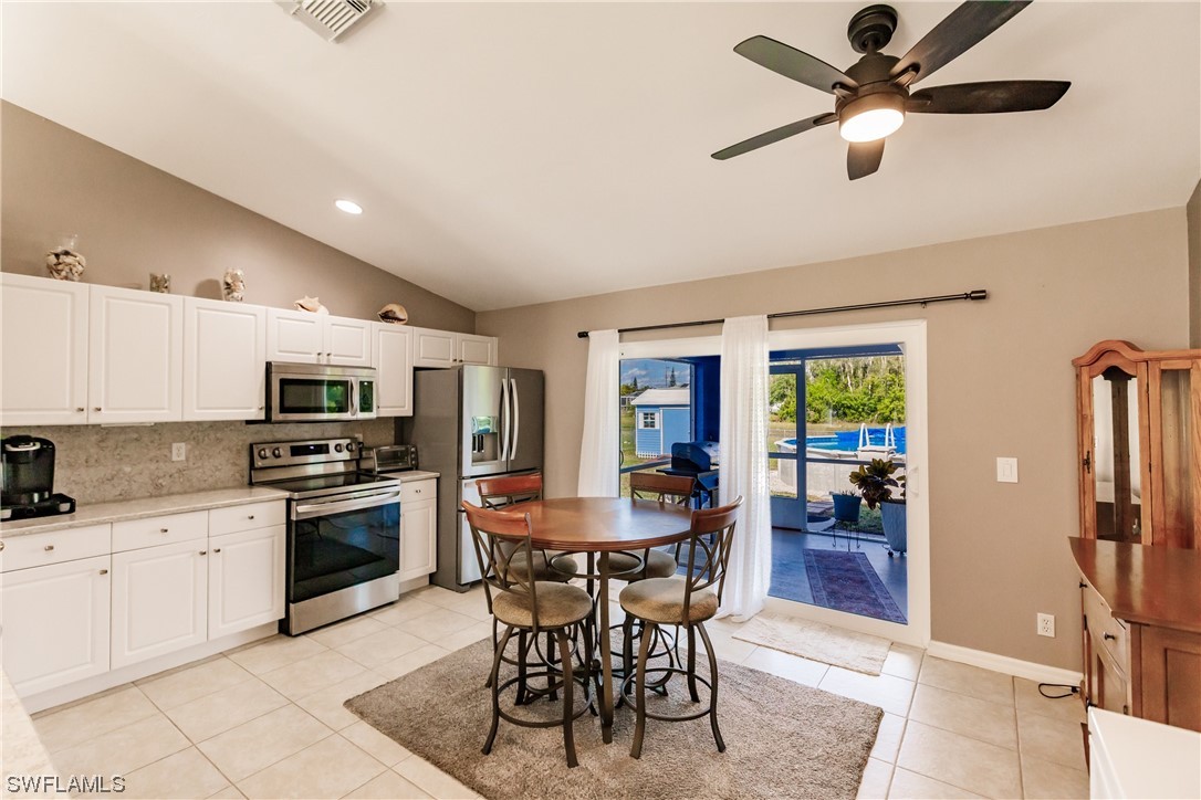 217 Manatee Street Fort Myers, FL 33913 - Photo 13 of 38 a kitchen with stainless steel appliances kitchen island granite countertop a sink a stove a dining table and chairs with wooden floor