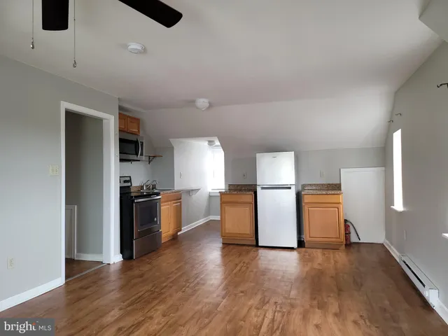 a kitchen with a refrigerator and wooden floor