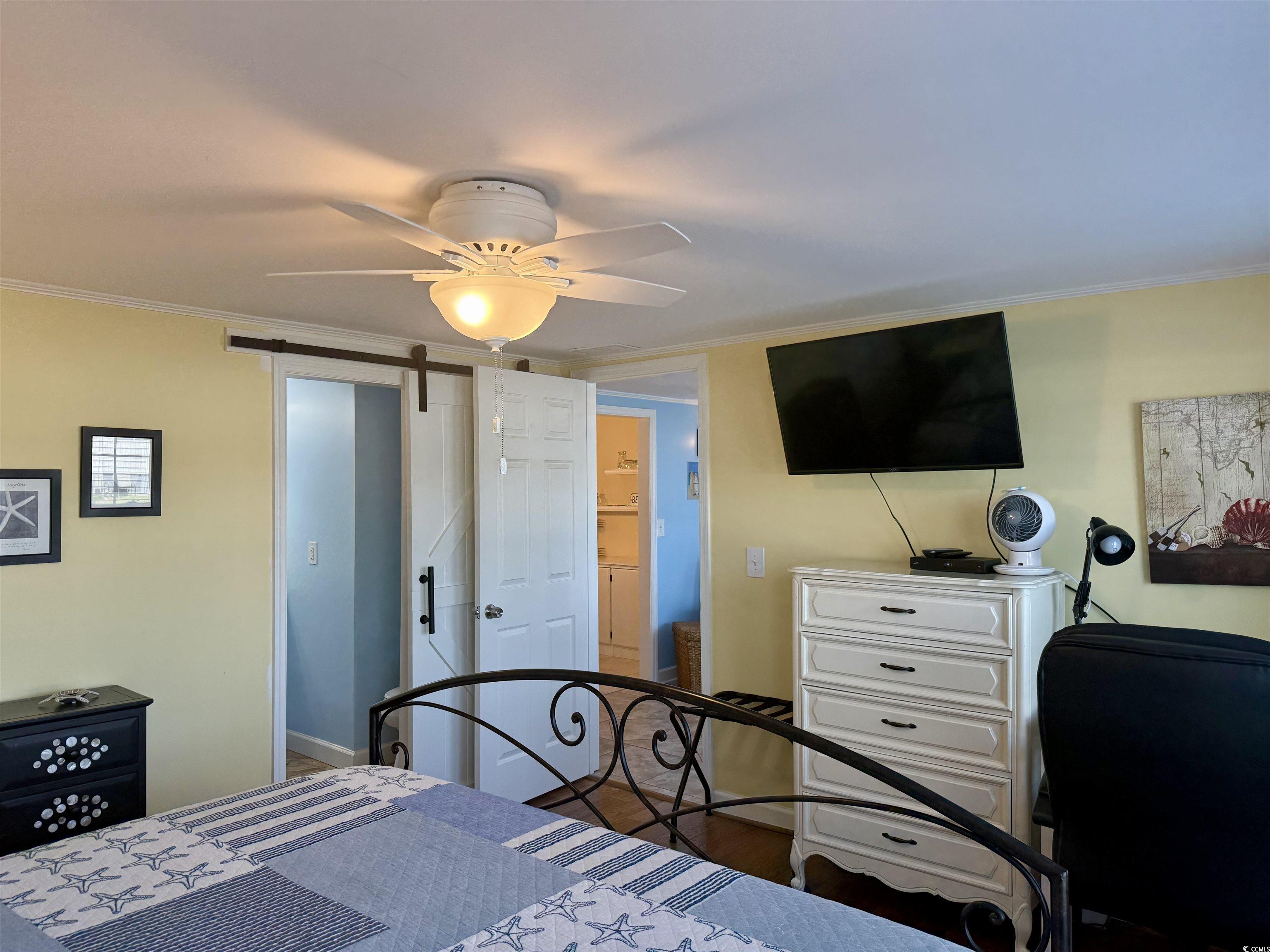 416 Oceanside Drive Surfside Beach, SC 29575 - Photo 14 of 37 Bedroom with a barn door, crown molding, a ceiling fan, and wood finished floors