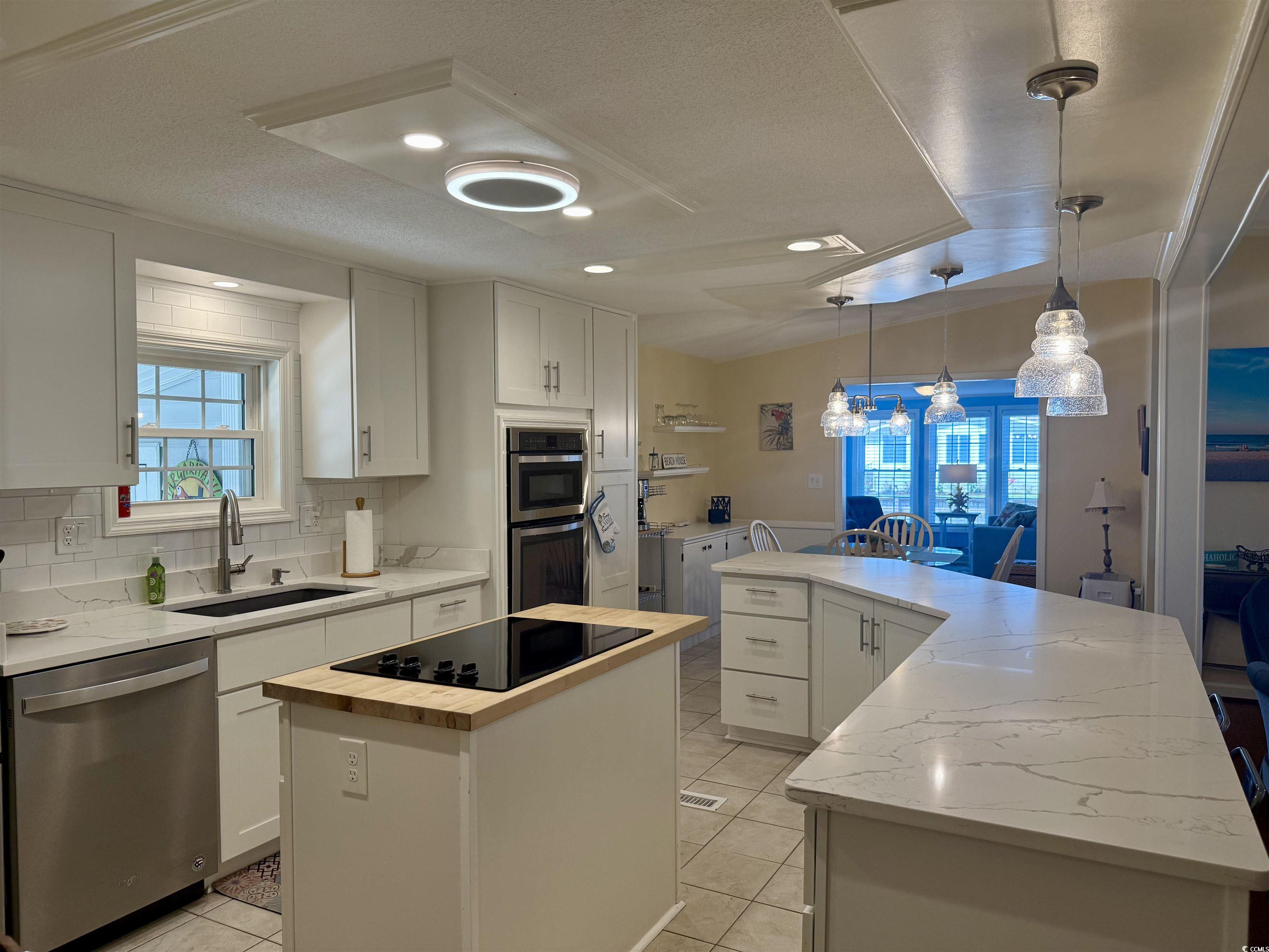 416 Oceanside Drive Surfside Beach, SC 29575 - Photo 3 of 37 Kitchen featuring appliances with stainless steel finishes, a kitchen island with sink, wood counters, light tile patterned floors, and white cabinets